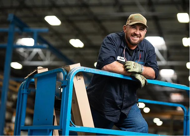 Smiling engineer in cap standing on scaffolding.