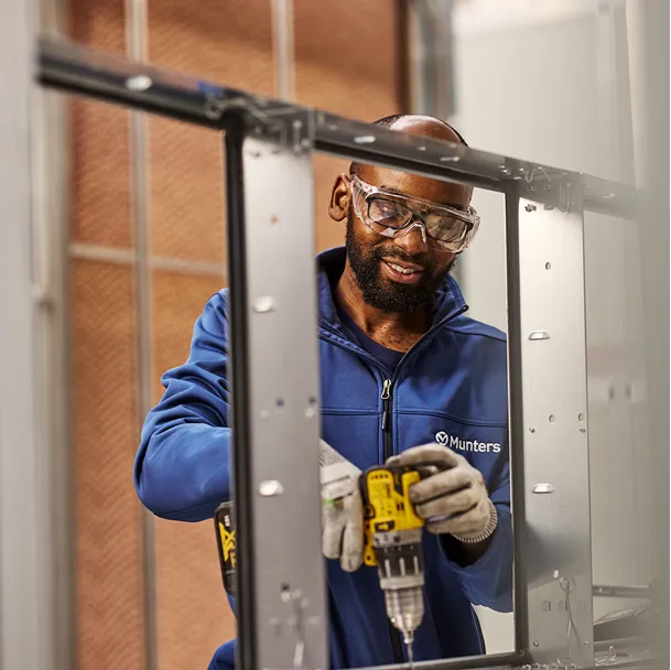 Employee in blue shirt and safety goggles working at a Munters liquid cooling equipment manufacturing facility