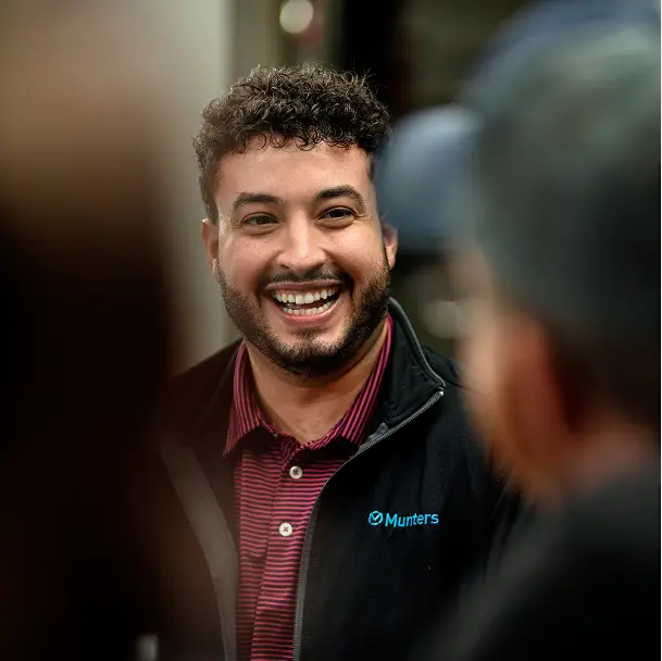 Smiling man wearing a striped polo-shirt and a black sweater with the Munters logo
