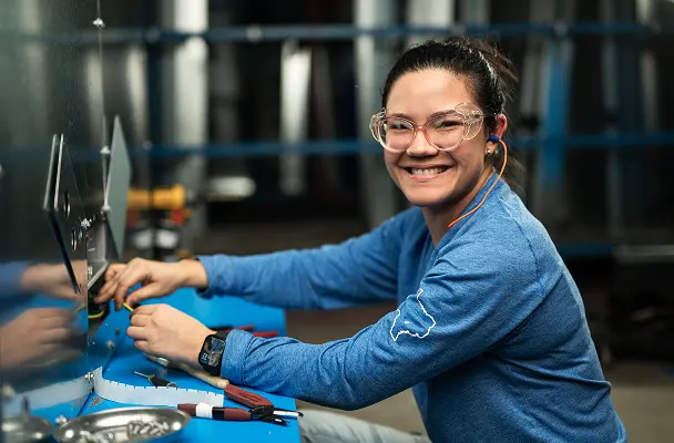 Woman smiling in blue sweatshirt while working in a Munters location